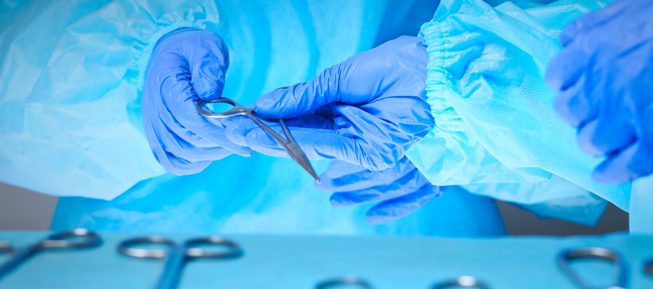 Close-up of of surgeons hands at work in operating theater toned in blue